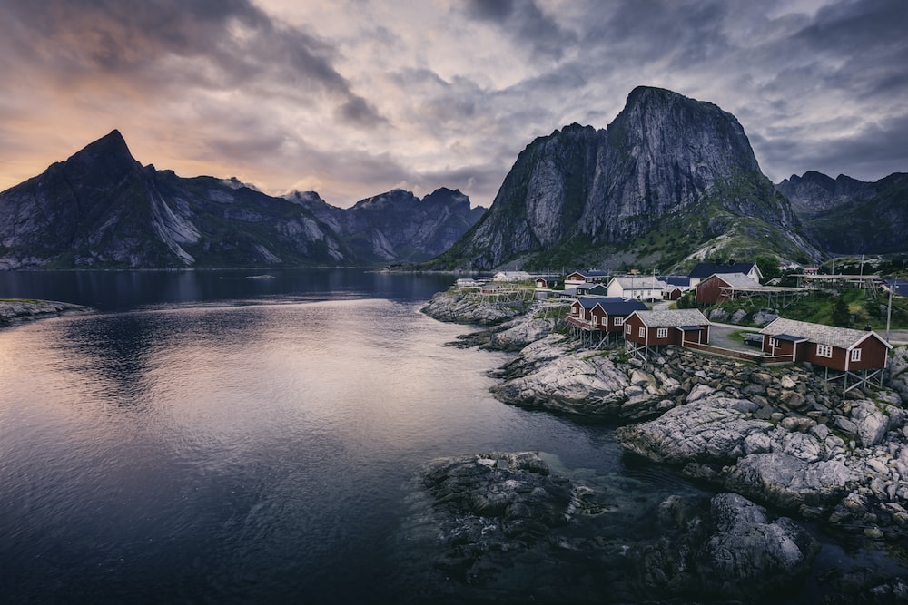 body of water near houses and mountains